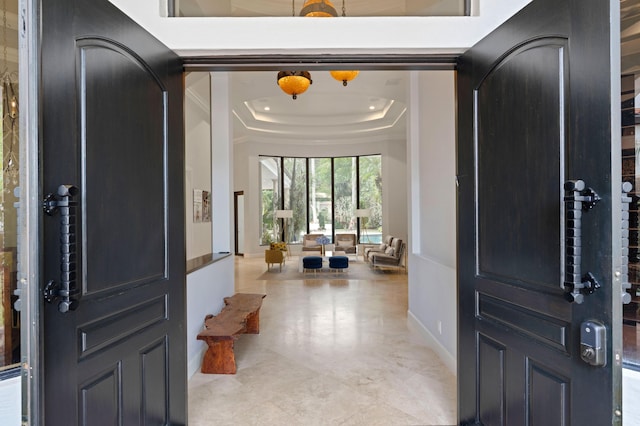 foyer with a raised ceiling and crown molding