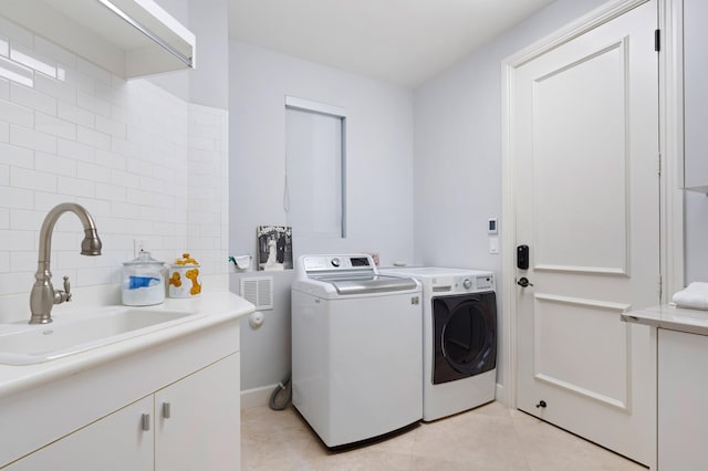 laundry room with light tile patterned floors, washer and clothes dryer, and sink