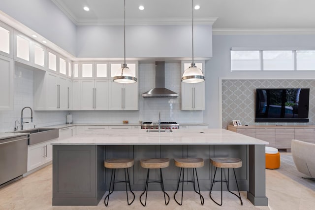 kitchen with dishwasher, pendant lighting, light stone counters, and wall chimney exhaust hood