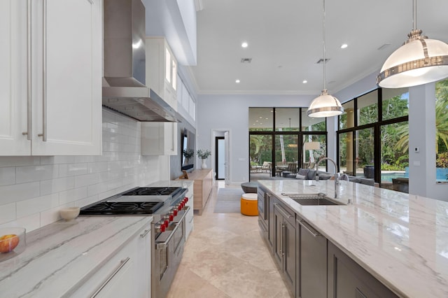 kitchen featuring white cabinetry, sink, wall chimney exhaust hood, range with two ovens, and decorative backsplash