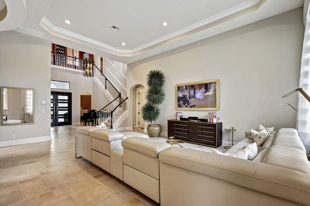 living room with a high ceiling, a tray ceiling, and crown molding