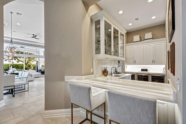 kitchen with white cabinetry, ceiling fan, a kitchen breakfast bar, wine cooler, and kitchen peninsula