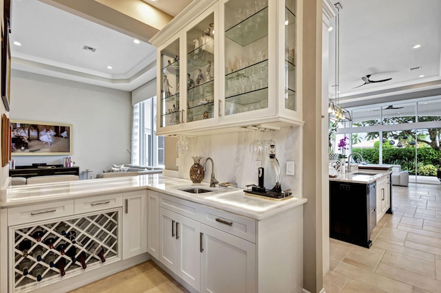 bar with white cabinets, a tray ceiling, ceiling fan, and sink