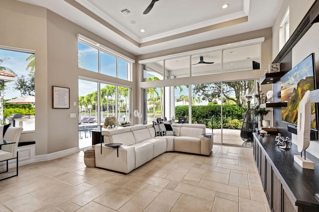 living room with a raised ceiling, ceiling fan, and a towering ceiling