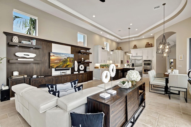 living room with a raised ceiling, a towering ceiling, and a chandelier