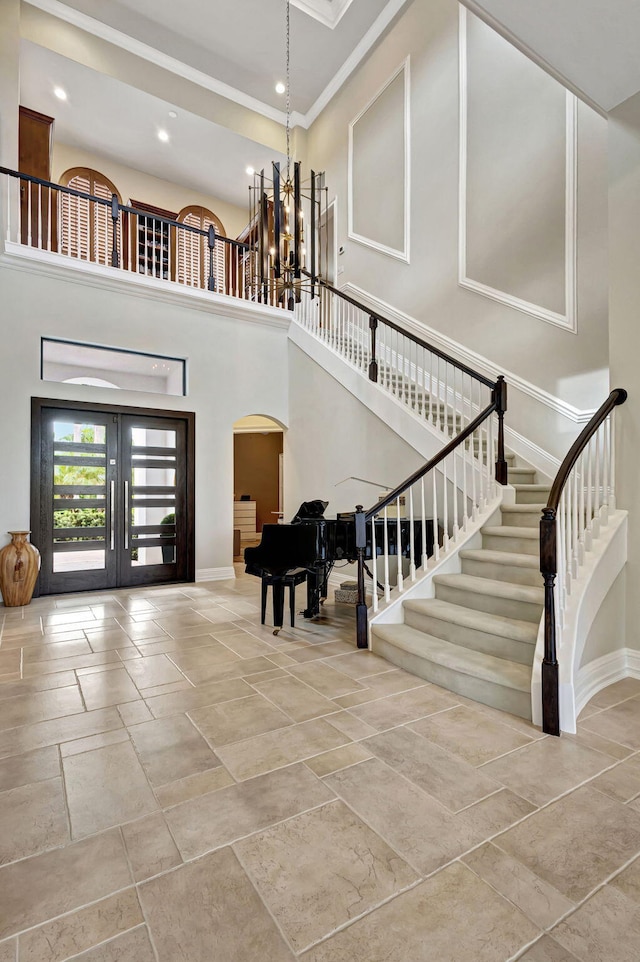 entrance foyer featuring a towering ceiling, ornamental molding, and a notable chandelier