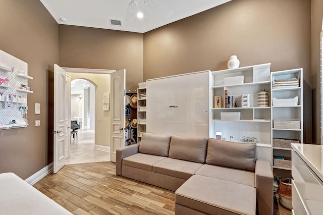 living room featuring ceiling fan, high vaulted ceiling, and light wood-type flooring