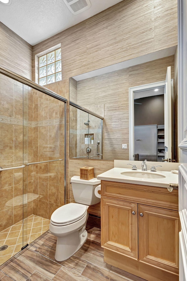 bathroom with vanity, wood-type flooring, a shower with shower door, and toilet