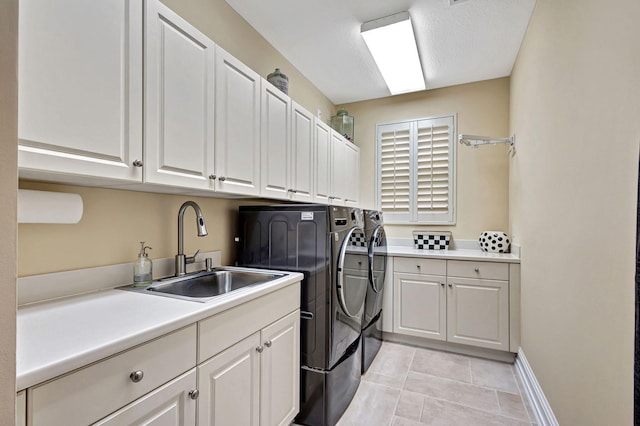 clothes washing area featuring cabinets, light tile patterned floors, sink, and washing machine and clothes dryer