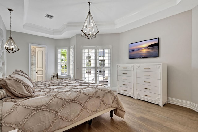 bedroom with a raised ceiling, wood-type flooring, and crown molding