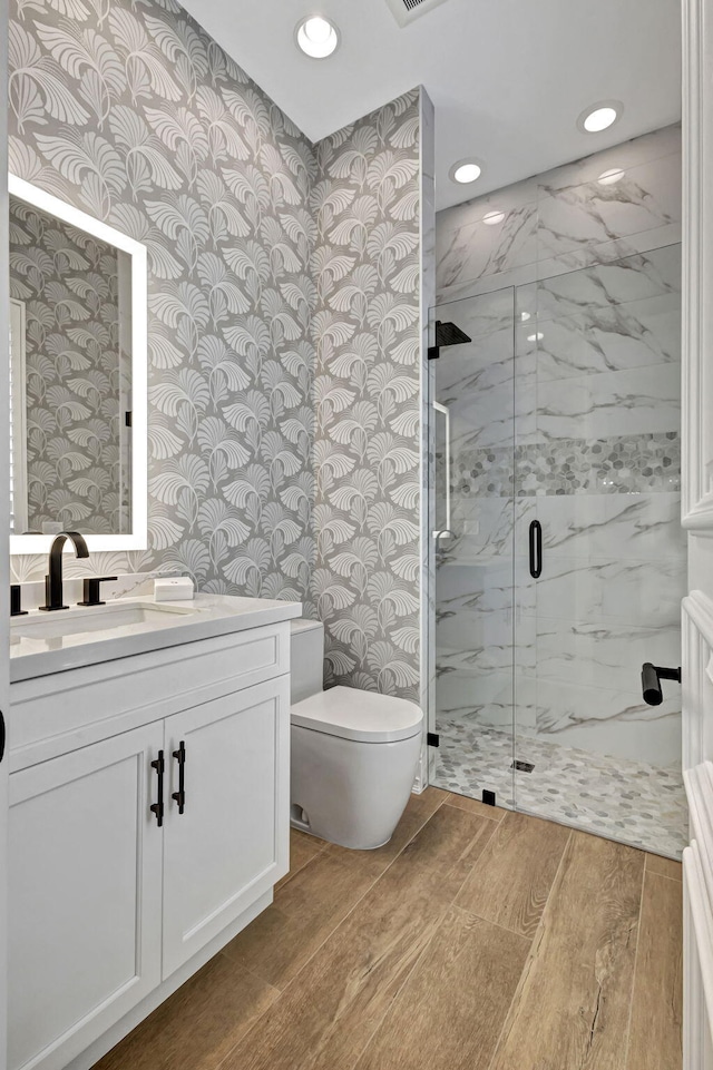 bathroom featuring hardwood / wood-style floors, vanity, toilet, and a shower with shower door