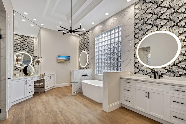 bathroom with a bath, a chandelier, vanity, and wood-type flooring