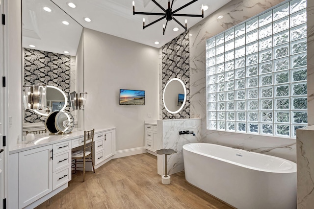 bathroom featuring a bathing tub, vanity, wood-type flooring, and a notable chandelier