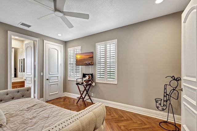 bedroom with parquet floors, a textured ceiling, ensuite bathroom, and ceiling fan