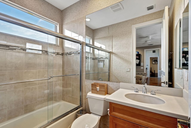 full bathroom featuring ceiling fan, toilet, bath / shower combo with glass door, and vanity