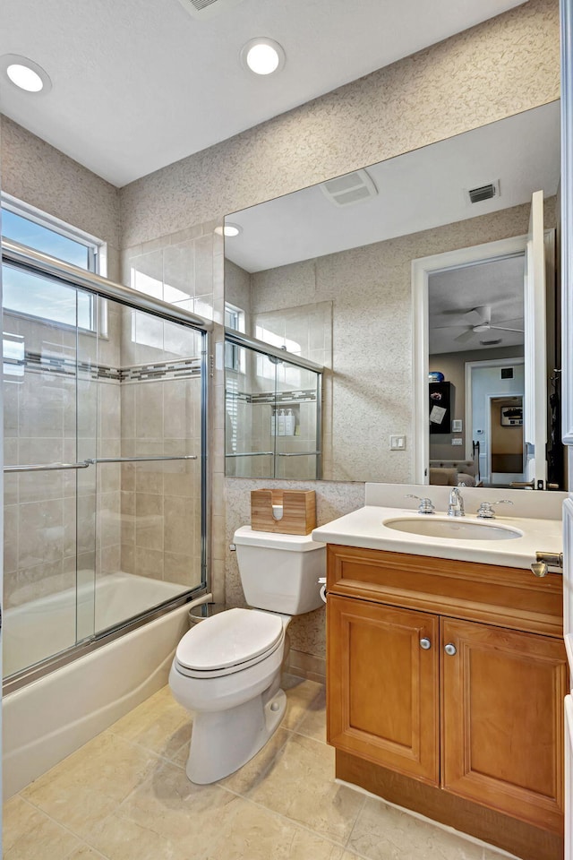 full bathroom with vanity, tile patterned floors, combined bath / shower with glass door, ceiling fan, and toilet