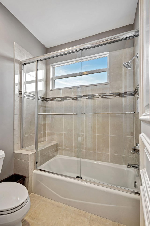 bathroom featuring shower / bath combination with glass door, tile patterned floors, and toilet