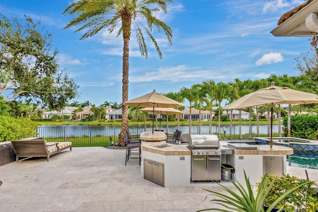 view of patio featuring exterior bar, a water view, grilling area, and exterior kitchen