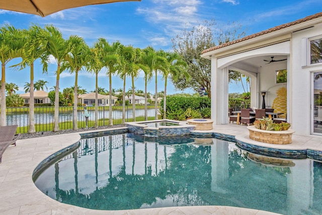 view of swimming pool with an in ground hot tub, a water view, ceiling fan, and a patio area