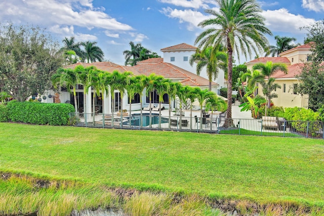 rear view of property featuring a yard, a fenced in pool, and a patio