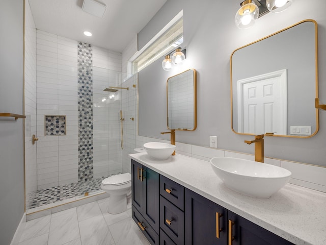 bathroom featuring a tile shower, vanity, and toilet