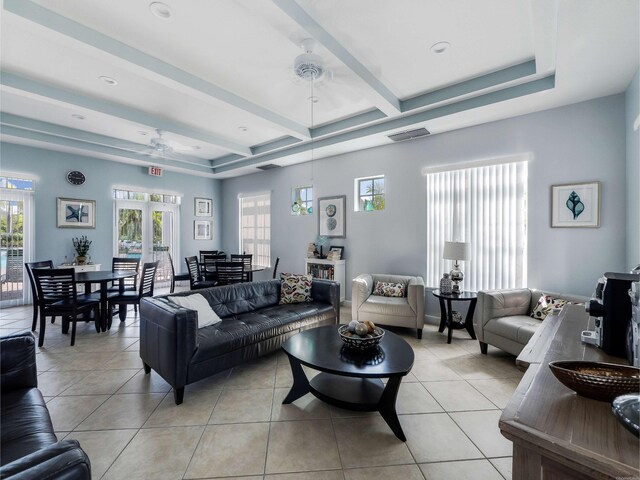 living room featuring beam ceiling, ceiling fan, a tray ceiling, and light tile patterned floors