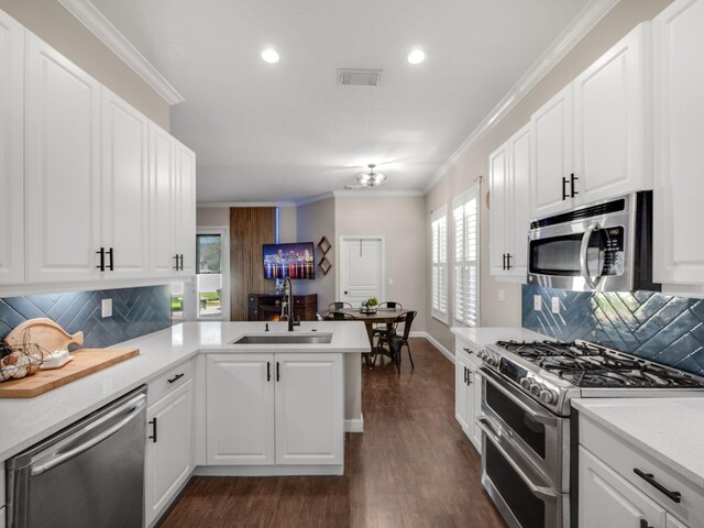 kitchen featuring dark wood-type flooring, white cabinets, sink, appliances with stainless steel finishes, and kitchen peninsula