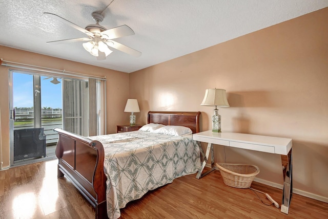 bedroom featuring access to exterior, a textured ceiling, hardwood / wood-style flooring, and ceiling fan