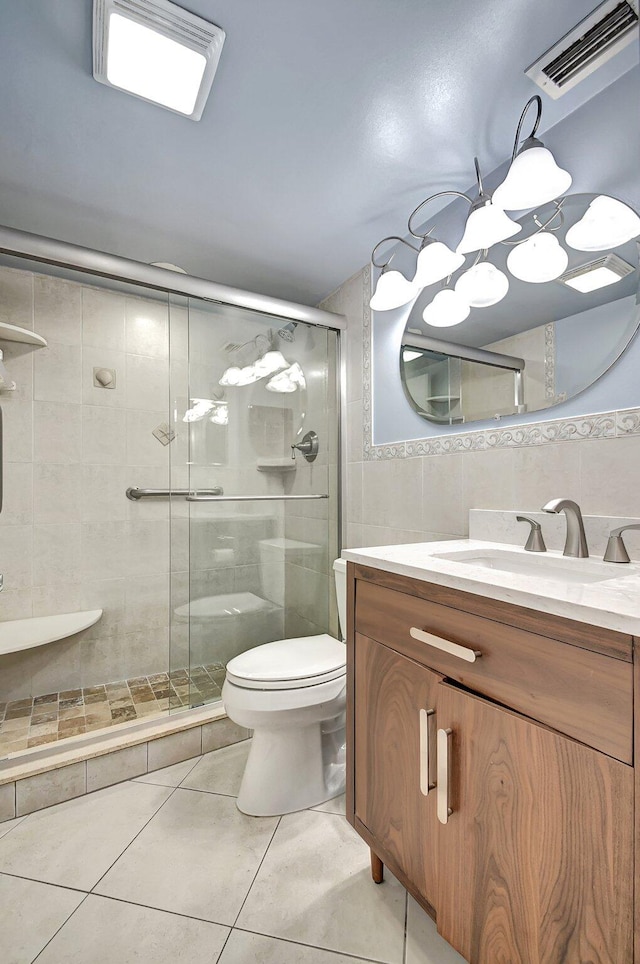 bathroom with vanity, a shower with door, tile patterned floors, toilet, and tile walls