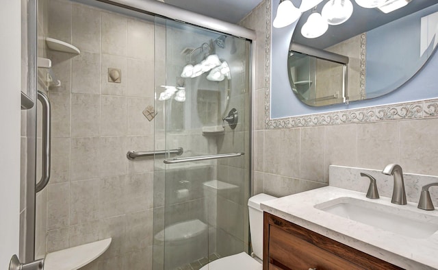 bathroom with vanity, toilet, a shower with door, and tile walls