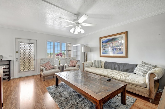 living room with ceiling fan, crown molding, a textured ceiling, and light wood-type flooring