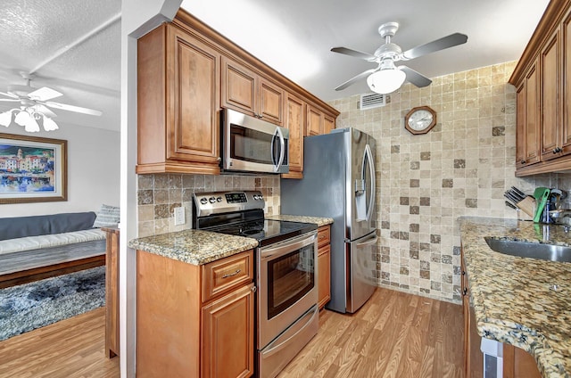 kitchen featuring ceiling fan, sink, stainless steel appliances, and light wood-type flooring