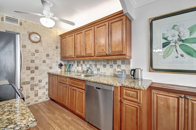 kitchen featuring sink, stainless steel appliances, light stone counters, backsplash, and light wood-type flooring