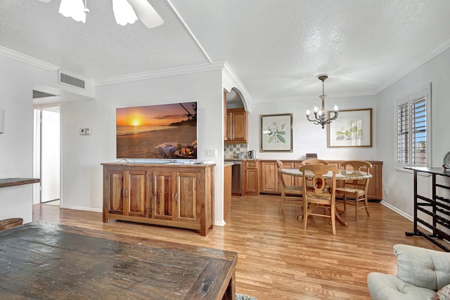 dining area with ceiling fan with notable chandelier, crown molding, light wood-type flooring, and a textured ceiling