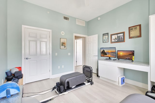 exercise room with built in desk and light hardwood / wood-style floors