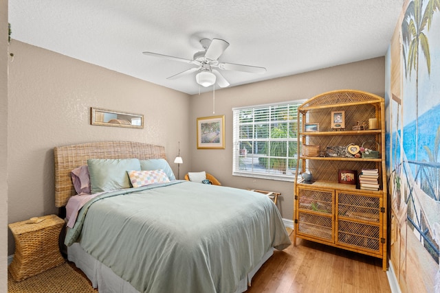 bedroom featuring a textured ceiling, light wood-type flooring, and ceiling fan