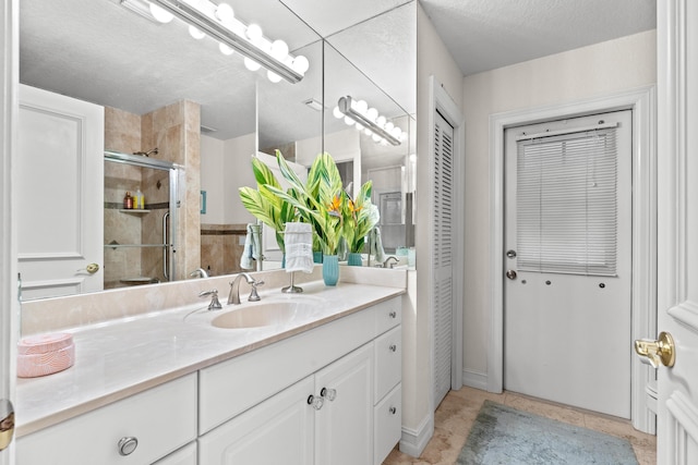 bathroom with a textured ceiling, vanity, walk in shower, and tile patterned floors