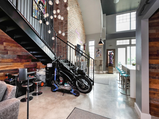 staircase featuring a towering ceiling, concrete floors, and wooden walls