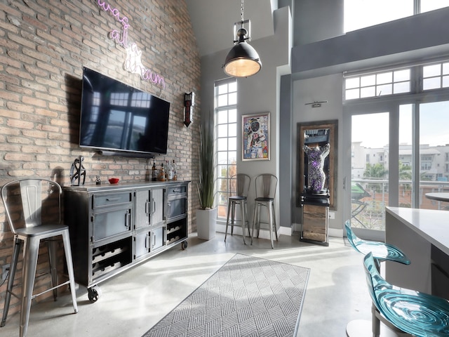 interior space with a high ceiling, plenty of natural light, and brick wall