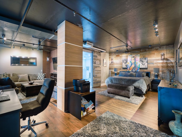 bedroom with wood-type flooring, track lighting, and wooden walls