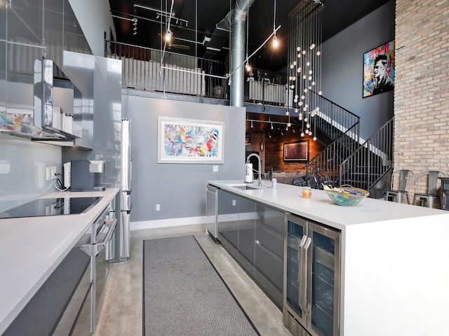 kitchen featuring a towering ceiling, sink, wine cooler, and black electric cooktop