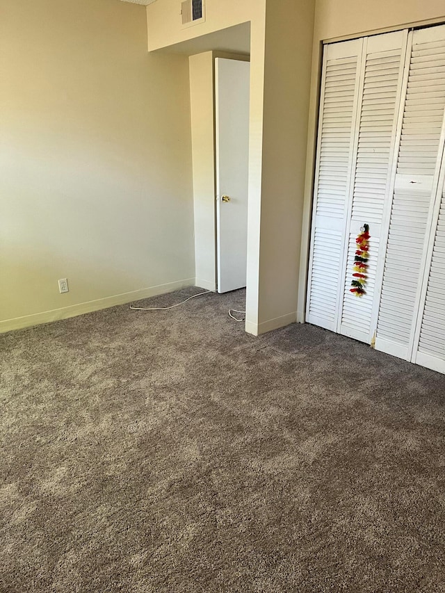 unfurnished bedroom with a closet and dark carpet