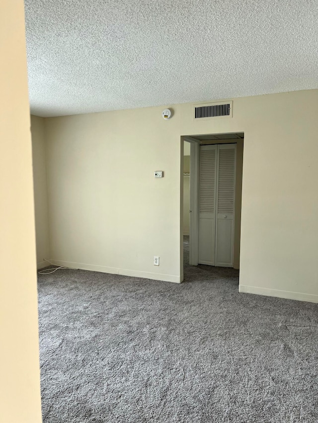 carpeted spare room with a textured ceiling