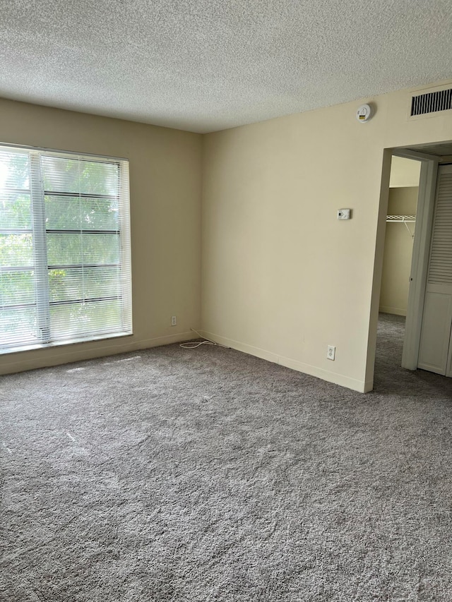 carpeted spare room with a textured ceiling