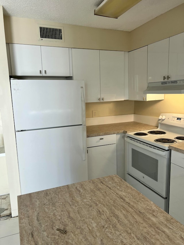 kitchen featuring a textured ceiling, white cabinets, and white appliances