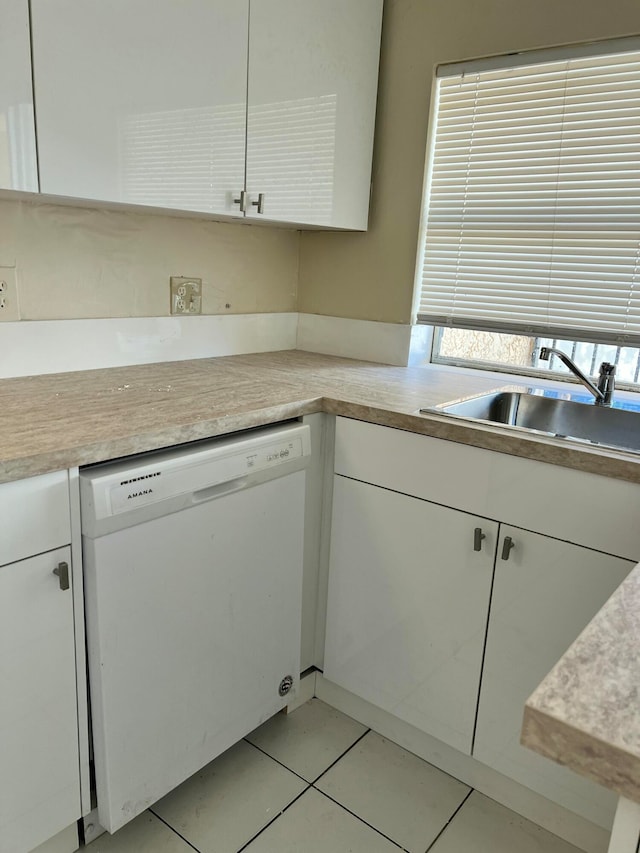 kitchen featuring white dishwasher, white cabinets, light tile patterned floors, and sink