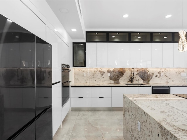 kitchen featuring white cabinetry, light stone countertops, modern cabinets, and a sink