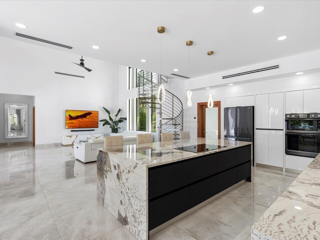 kitchen featuring an inviting chandelier, hanging light fixtures, black electric cooktop, a towering ceiling, and a large island