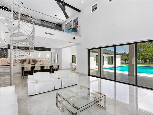 living area with stairway, marble finish floor, a high ceiling, and ceiling fan