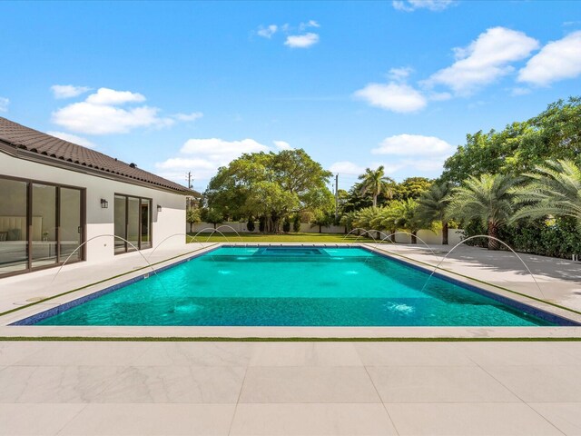 pool at dusk with an outdoor pool and a patio